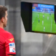 A referee conducting a video review with the aid of VAR to overturn or confirm a decision