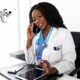 Smiling black woman speaking on smartphone in office