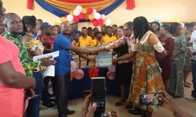 Mr Afetor handing a book to the head of beneficiary school