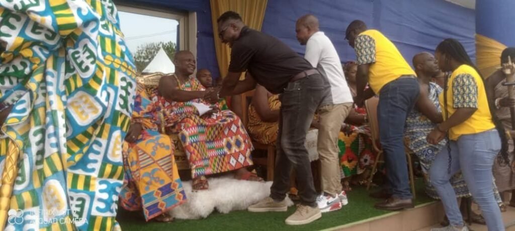 Togbe Afede (seated)receiving a
handshake from staff of MTN