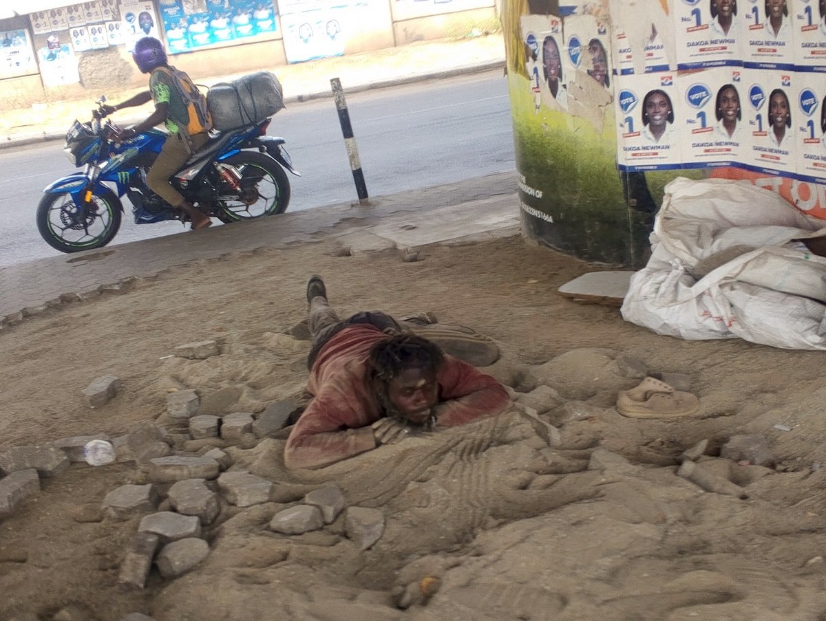 A homeless man sleeping in the sand close to the removed blocks